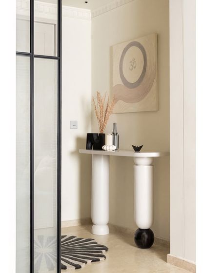 The journey into KAIA begins in this minimal yet intentional foyer. A bespoke console stands against the wall, adorned with a spiritual ‘OM’ art piece we co-designed with an artist. The space is grounded by a custom rug with a scalloped circumference, echoing the home's curved elements.