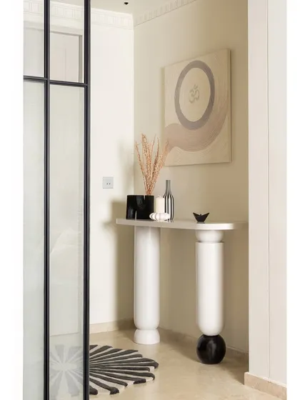 The journey into KAIA begins in this minimal yet intentional foyer. A bespoke console stands against the wall, adorned with a spiritual ‘OM’ art piece we co-designed with an artist. The space is grounded by a custom rug with a scalloped circumference, echoing the home's curved elements.