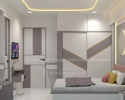 This bedroom features a dual-tone wardrobe with a geometric design that complements the headboard wall. The integrated TV unit and dresser make it a highly functional space.