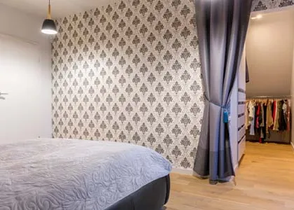 Curtains aren't just for windows. In this bedroom, I used a stylish, heavy-duty grey curtain as a flexible room divider to conceal a walk-in closet area. This is a practical and cost-effective solution for creating distinct zones within a room without building a permanent wall.