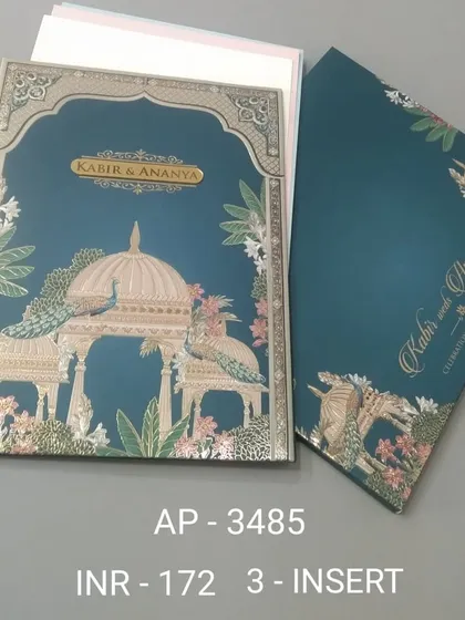 A rich teal invitation featuring peacocks perched on a gazebo, with silver foil accents. This three-insert card is perfect for an elegant evening ceremony or reception.