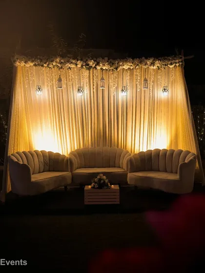 An elegant cabana lounge for a wedding reception. The cozy seating is set under a beautifully draped canopy with hanging lanterns, creating a perfect spot for guests to relax.