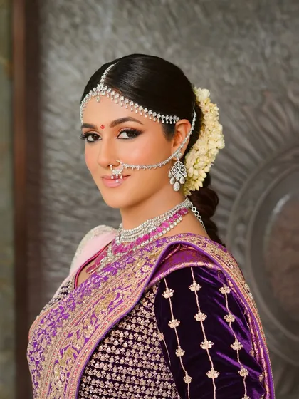 For this traditional ceremony, I designed a look that was both regal and ethereal. The makeup features softly sculpted features and luminous skin, harmonizing perfectly with the rich purple silk saree and classic diamond matha patti, creating a timeless bridal portrait.