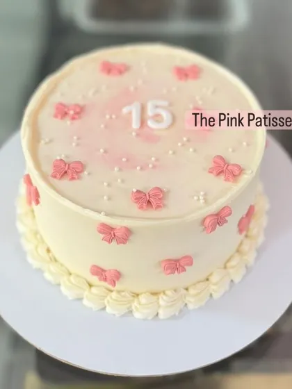 A sweet and simple cake for a 15th birthday, decorated with small pink bows and pearls.