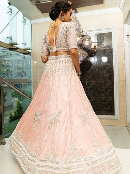 Twirl into a fairytale with this baby pink bridal lehenga. I designed it with intricate horse embroidery on the raw silk skirt and paired it with a heavily handworked blouse and a delicate net dupatta for a truly heavenly look.