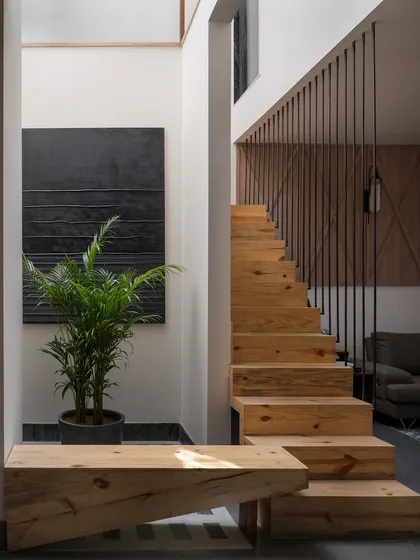 A detail of the pinewood staircase and custom bench. The warm grain of the wood catches the light, adding texture and variation to the compact plan.