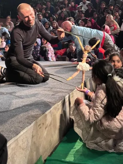 A young audience member gets an up close and personal moment with a delicate ballerina marionette from Russia's 'Theatre in the Pocket'. We curate interactive shows that break the barrier between the stage and the audience, creating cherished memories for families.
