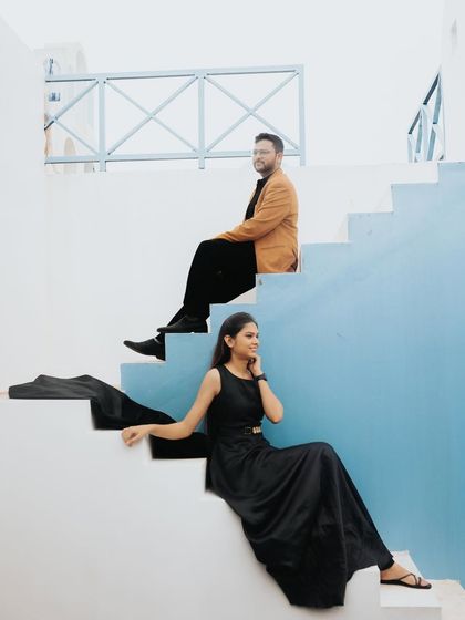 A modern and stylish pose on a staircase with a vibrant blue wall. The composition creates strong lines and a contemporary feel.