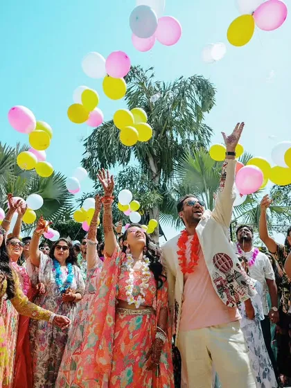 A moment of pure happiness as the couple and their friends release balloons into the sky during a daytime celebration.