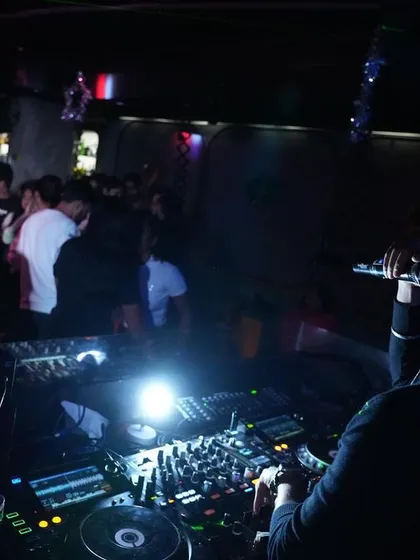 An over the shoulder view from the DJ booth, showing my perspective as I control the music and interact with the crowd on the dance floor.
