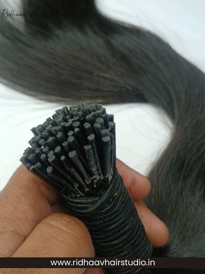 Holding a bundle of our I-Tip wavy extensions, this shot highlights the hair's texture and the neatly bonded tips ready for installation.
