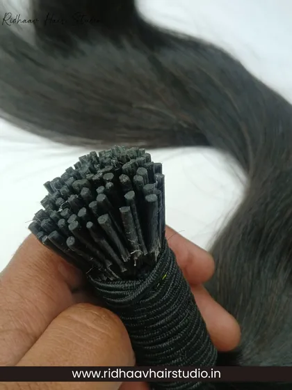 Holding a bundle of our I-Tip wavy extensions, this shot highlights the hair's texture and the neatly bonded tips ready for installation.