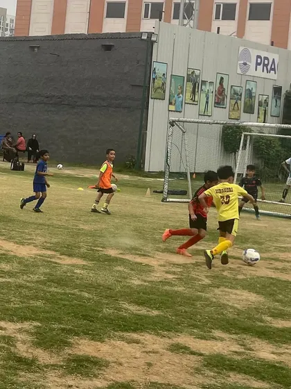 A player dribbling towards the goal in a match. Friendly matches are key to skill refinement and building confidence.