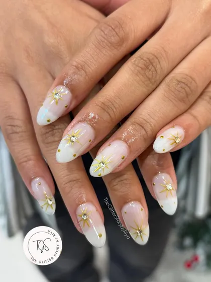 A dreamy, celestial-inspired set with a milky white ombré base, adorned with gold starburst charms and tiny gold studs.