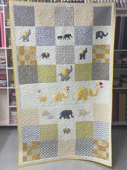 A cheerful baby quilt with appliquéd elephants in shades of yellow and grey.