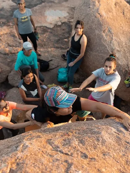 A top-down view of our crew spotting a climber as she reaches the top of a boulder. We're all in it together, celebrating every success.