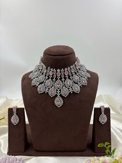 A heavy, silver-plated AD necklace set with a peacock-inspired feather design. This statement piece is available in blue, green, pink, and all-white.