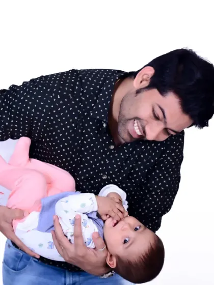 A candid shot of a father playfully lifting his baby boy, both smiling.