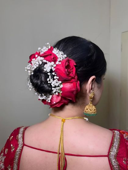 A detailed shot of the elegant bridal bun adorned with red roses and baby's breath.