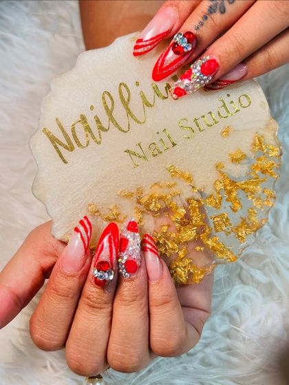 Karwachauth nails that are all about the drama. This set has it all: long stiletto shape, bold red color, glitter, and tons of 3D gems and hearts for a truly festive look.