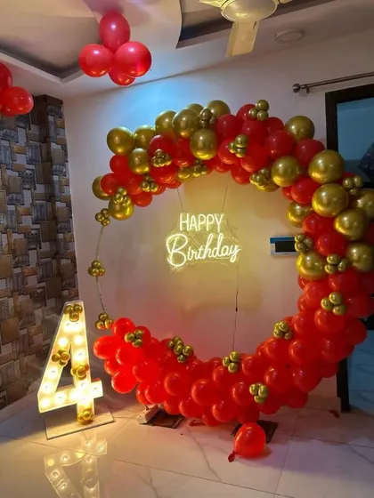 This vibrant red and gold balloon ring is perfect for making a statement. Paired with a 'Happy Birthday' neon sign and a light-up marquee number '4', it creates a fantastic photo spot for a child's birthday party.