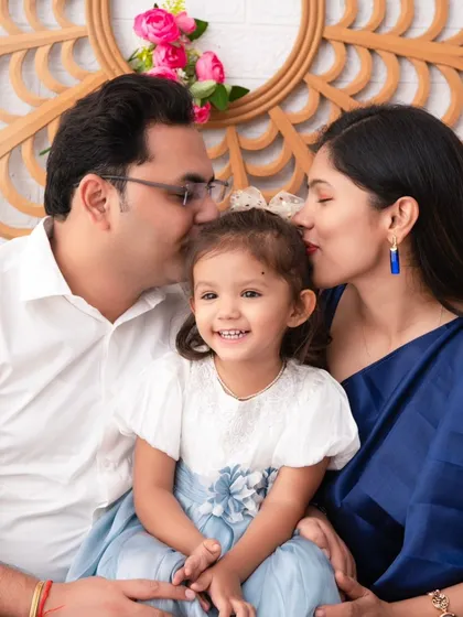 A portrait of pure family happiness. The parents shower their smiling daughter with kisses, creating a moment overflowing with love and joy.