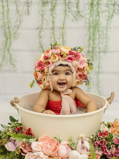 A big, beautiful smile from this six-month-old. The floral bonnet and bathtub setup create such a unique and memorable photo.