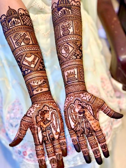 This design captures the beautiful varmala ceremony. The palms feature the bride and groom exchanging garlands, while the arms are decorated with traditional symbols like a doli and shehnai.