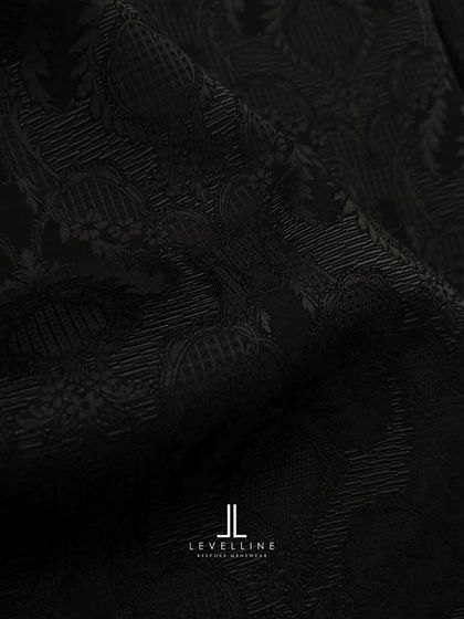 A sneak peek into our studio, showcasing the intricate black-on-black jacquard fabric and the design sketch for a client's special outfit.