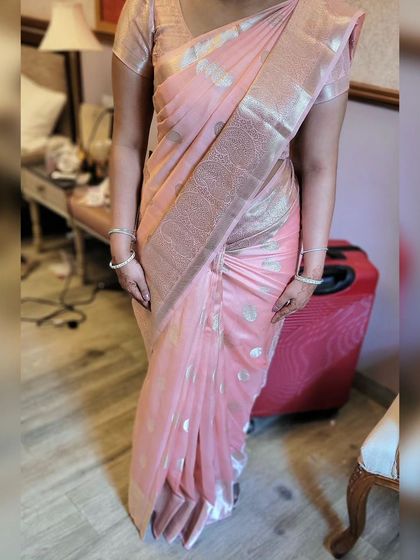 The full view of the soft pink silk saree drape. It's a simple, elegant style that is perfect for any daytime event or formal gathering.
