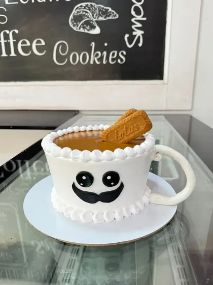 A delicious-looking coffee cup cake, this time with a Lotus Biscoff biscuit dipping into it. It's a perfect design for someone who loves their coffee and sweets.