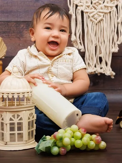 A burst of laughter from a one-year-old boy playing with props during his rustic-themed birthday shoot.