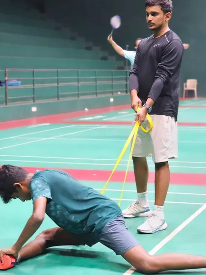A coach assists a player with a deep stretch using a resistance band, ensuring proper recovery and flexibility to prevent injuries.