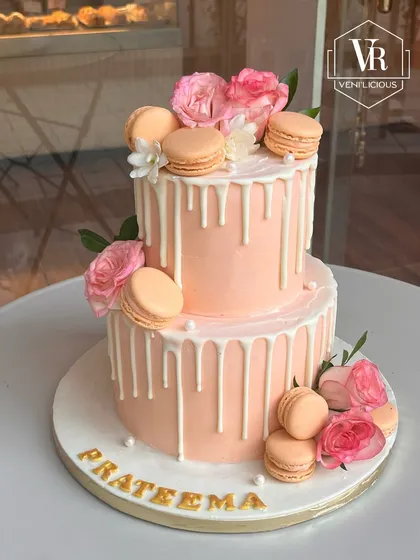 A lovely two-tier peach drip cake I made for my school teacher's 60th birthday. It's decorated with a white chocolate drip, fresh pink roses, and delicate macarons, combining classic elegance with modern trends.