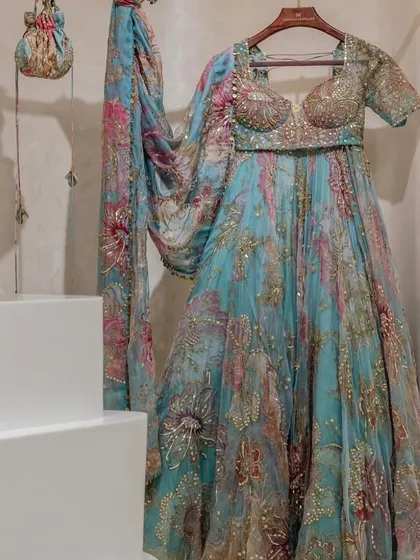 This beautiful turquoise floral lehenga comes with a matching potli bag. It's the small details that complete the look for your special event.