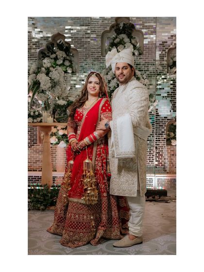 A classic formal portrait of the newlyweds, standing proudly together against the elegant backdrop of their wedding decor.