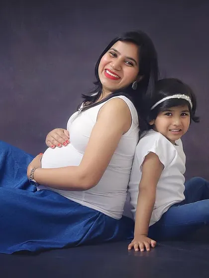 A sweet back-to-back pose with her daughter. This studio family maternity photo is a lovely way to capture the bond between mother and child before the new baby arrives.