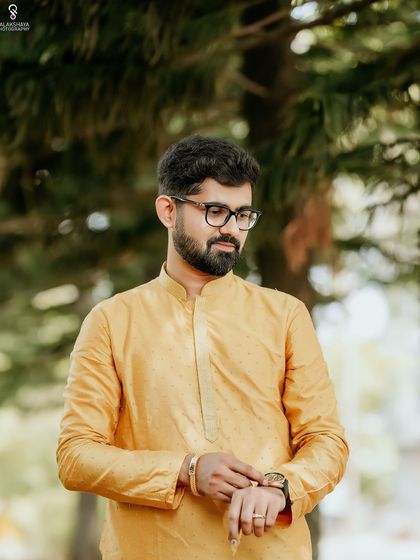 A classic portrait of the groom, looking thoughtful as he adjusts his watch before the Haldi ceremony.