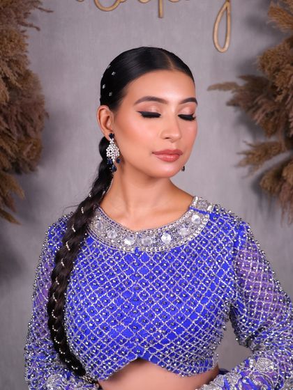A close-up on the soft eye makeup and clean, slicked-back hairstyle with a braided ponytail, perfect for a modern party look.