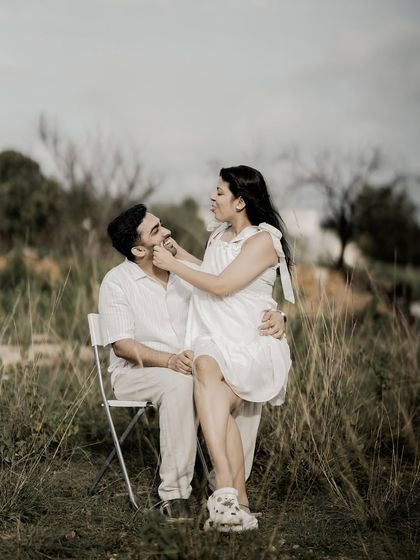 A sweet and playful moment, with the bride sitting on the groom's lap and gently pinching his cheek.