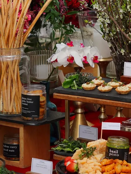 A magnificent Christmas grazing table we catered for a festive event. It features an abundant spread of cheeses, canapés like our gluten-free peanut butter cookies, basil pesto, and various artisanal nuts and crackers.