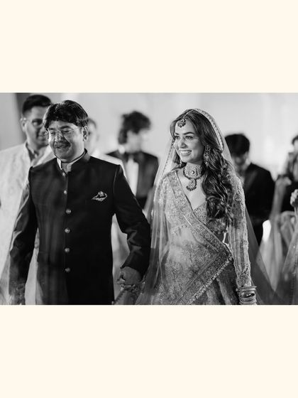 A beautiful black and white shot of bride Chitranksha walking with her father. This poignant moment captures the love and pride shared between a daughter and her dad on the wedding day.