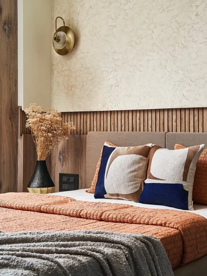 The guest bedroom, showcasing the wooden fluted wall panel and concrete-textured walls for a calm, earthy ambiance.