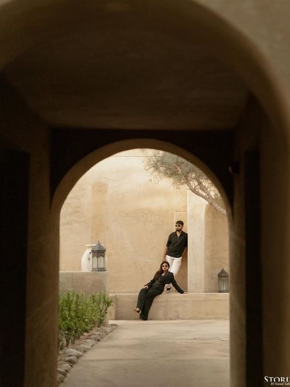 An artistic shot of the couple framed through a dark archway, creating a sense of intimacy and mystery.