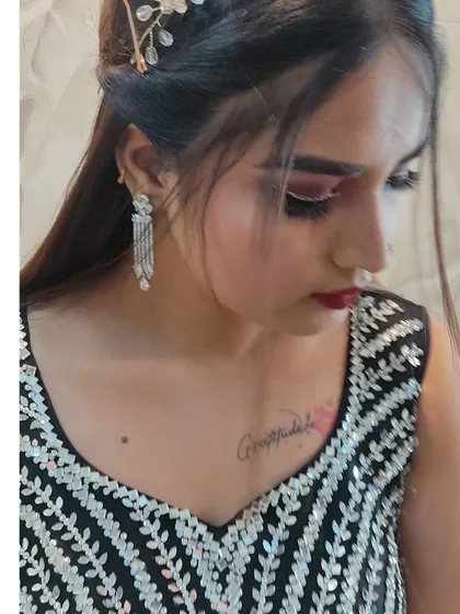 A close-up of a glamorous evening look. It features a sharp winged liner, dramatic lashes, and a deep red lip, paired with sparkling diamond earrings.