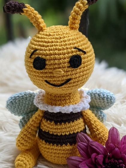 A happy little honey bee with light blue wings and a ruffled white collar.