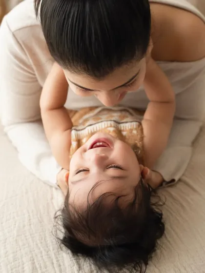 An overhead shot of a mother and baby sharing a happy, playful moment on a soft blanket. This perspective creates a unique and intimate portrait.