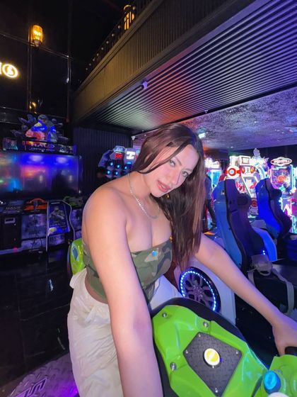 A fun, playful look with a camo tube top and beige pants at an arcade.