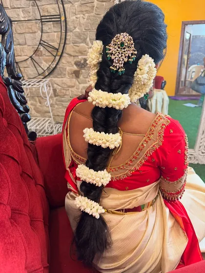 A detailed look at Preethi's traditional engagement hairstyle from the back. The neat braid is beautifully decorated with jasmine flowers and a stunning jewelled hairpiece at the crown.