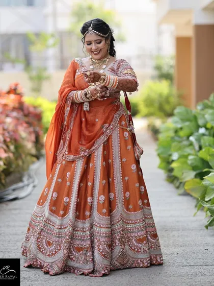 A candid moment of the bride, happy and radiant in her unique orange bridal attire.